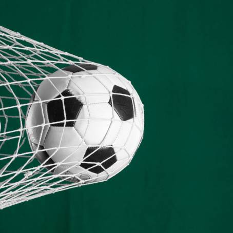 Black and White Soccer Ball CloseUp on Green Grass with Goalpost and Net Background