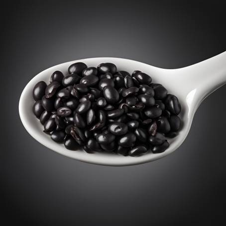 Black Beans in White Ceramic Spoon Against Black Background High Contrast Food Photography