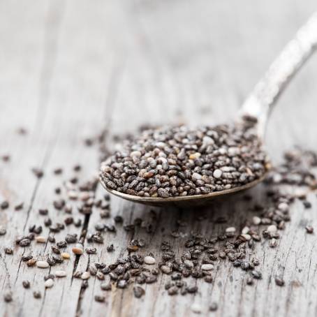 Chia Seeds in a Wooden Spoon with Nutritional Information on a Wooden Surface