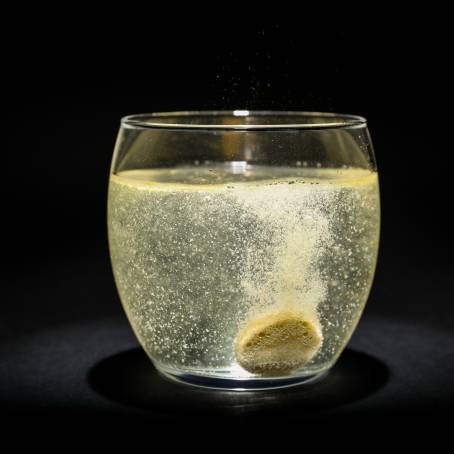 CloseUp of Orange Vitamin C Dissolving in Water Bubbles and Blue Background