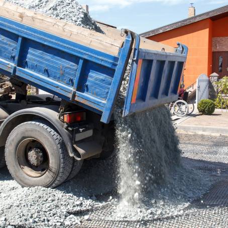 Excavator with Crushed Stone and Sand Loading Truck White, Gray, and Black Gravel Piles on Site