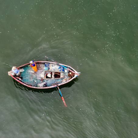 Fisherman Casting Net from Vintage Boat in Coral Sea