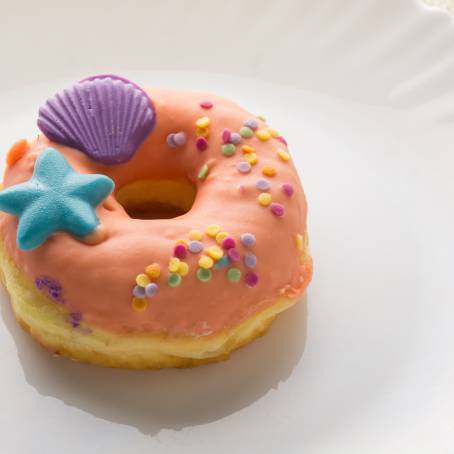 Fresh Strawberry Glazed Donuts with Sprinkles on White Surface