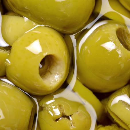 Green Olives and Slices Floating on White Background