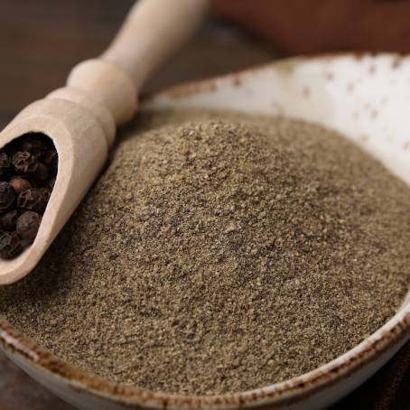 Ground Pepper and Peppercorns in Wooden Bowl Close Up