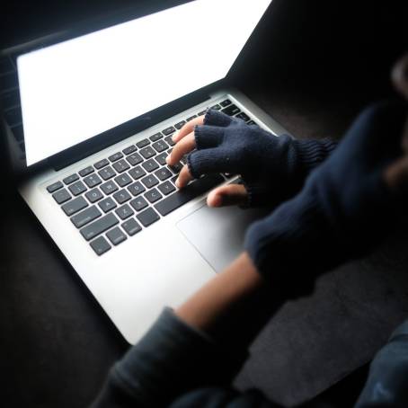 Hacker in Dark Room with Laptop and Mobile Device Typing