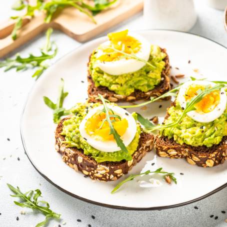 Healthy Breakfast Concept Soft Boiled Eggs with Dill on Whole Grain Toast, Close Up on White Plate