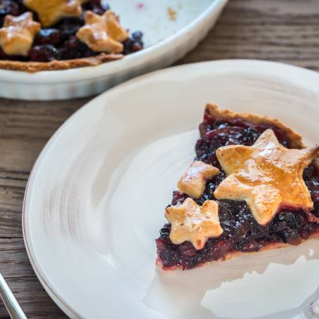 Open Mince Pie with Red Christmas Background on Wooden Table Closeup