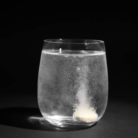 Orange Vitamin C Dissolving in Glass of Water with Bubbles CloseUp