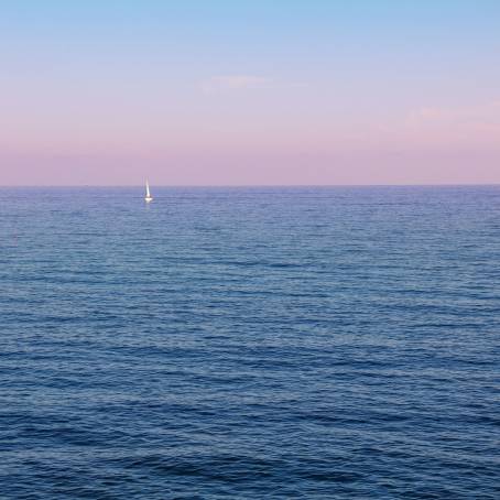 Peaceful Pink and Purple Sunset Over Calm Ocean Under a Clear Blue Sky