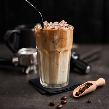 Refreshing Iced Milk Tea with Whipping Cream in Takeaway Glass on Grass Table