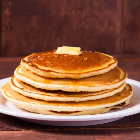 Stack of American Pancakes with Syrup and Butter on White