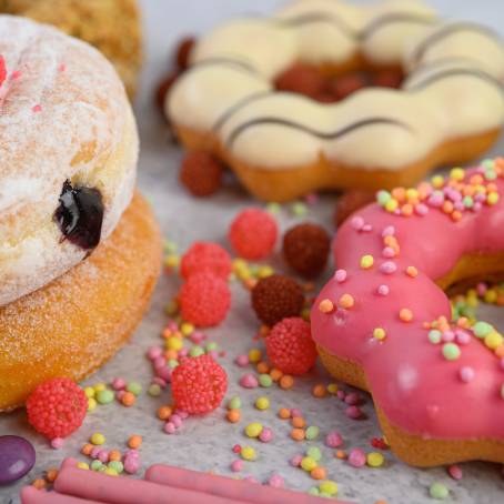 Vibrant Strawberry Glazed Donuts with Fun Sprinkles on White Background